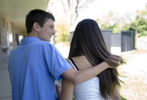 A high school student with disabilities puts his arm around a girl friend's shoulder.