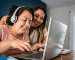 Caregiver helps a person served work on a laptop