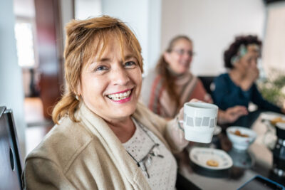Mom holding coffee cup at a social meeting with other parents
